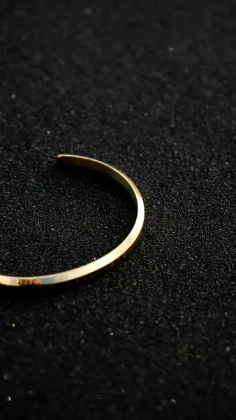A gold bangle on black sand