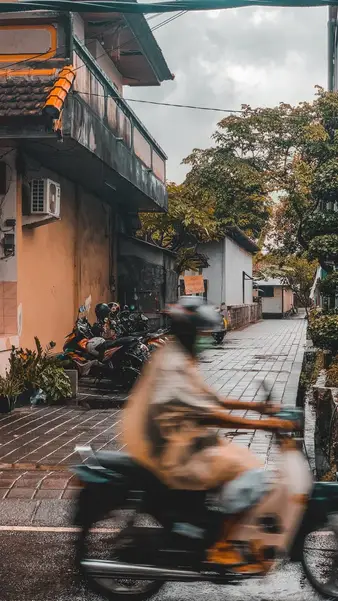 A motorbike blurring past on a wet village street