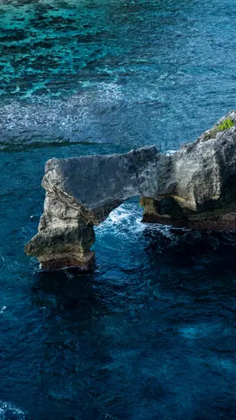 A limestone arch in the water, seen from the cliff top