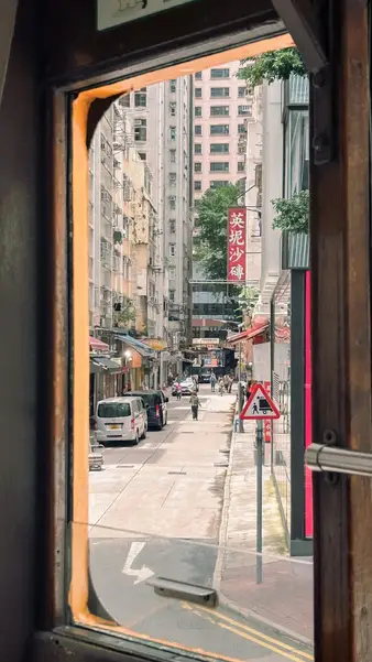 A street framed by the window of a tram