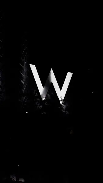 A lit W sign over the treetops